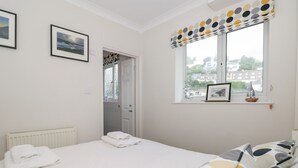 A bedroom with a bed, a window with a view, a door, and a radiator. - Huffin (Dartmouth)
