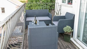 A balcony with wicker furniture, a bottle of champagne, and a potted plant.