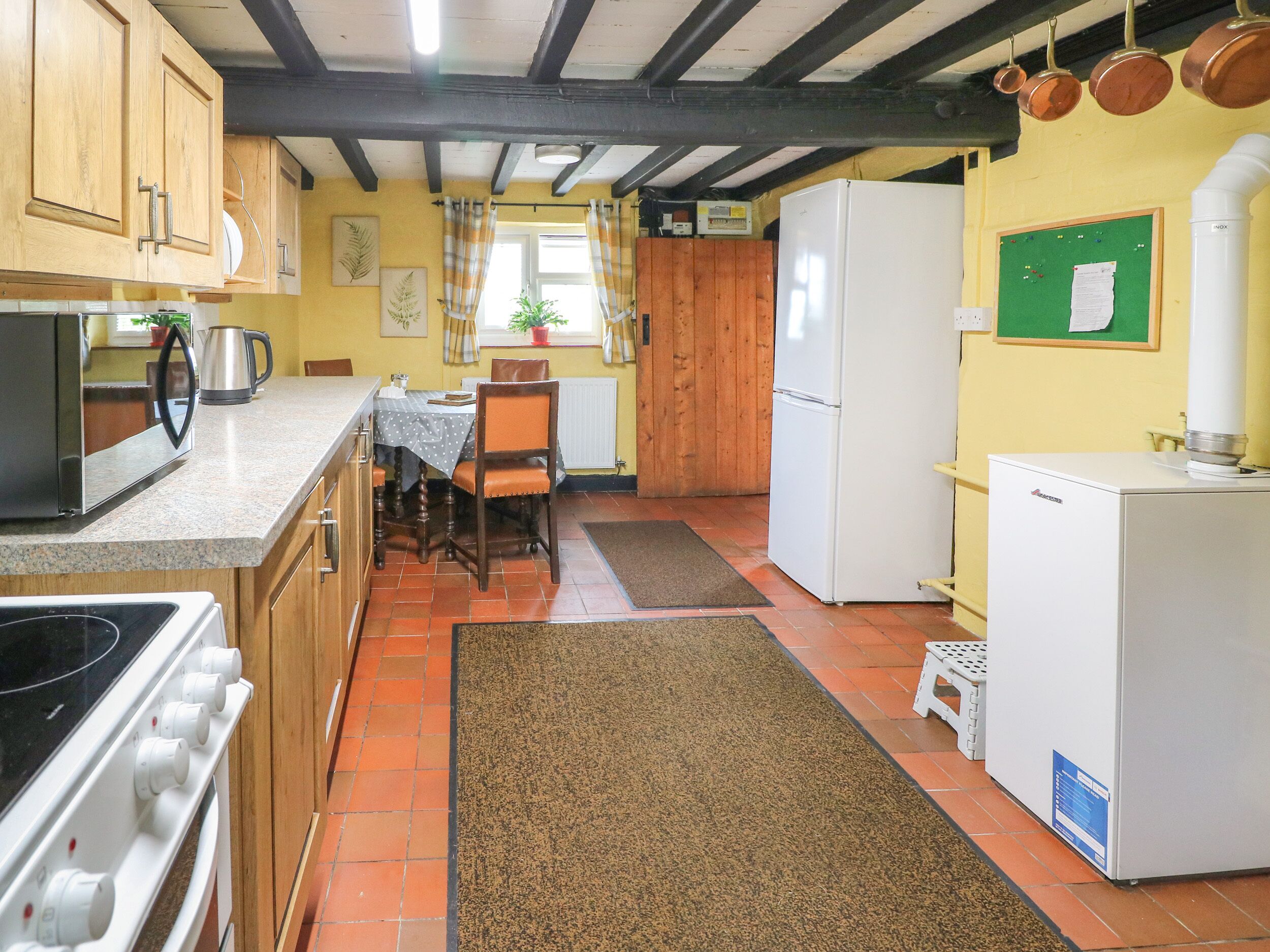 Une cuisine avec des meubles de rangement en bois, une cuisinière, un réfrigérateur et une table à manger avec des chaises.
