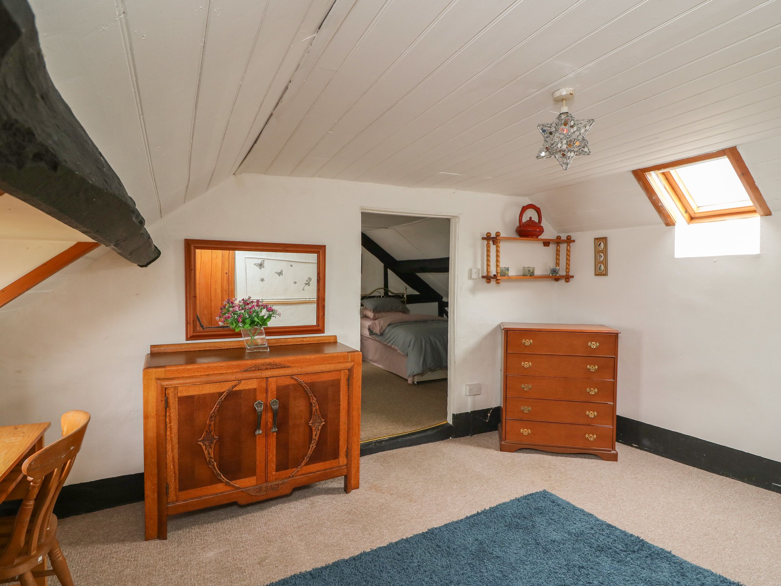 A room with a wooden cabinet, a dresser, a mirror, and a small window.