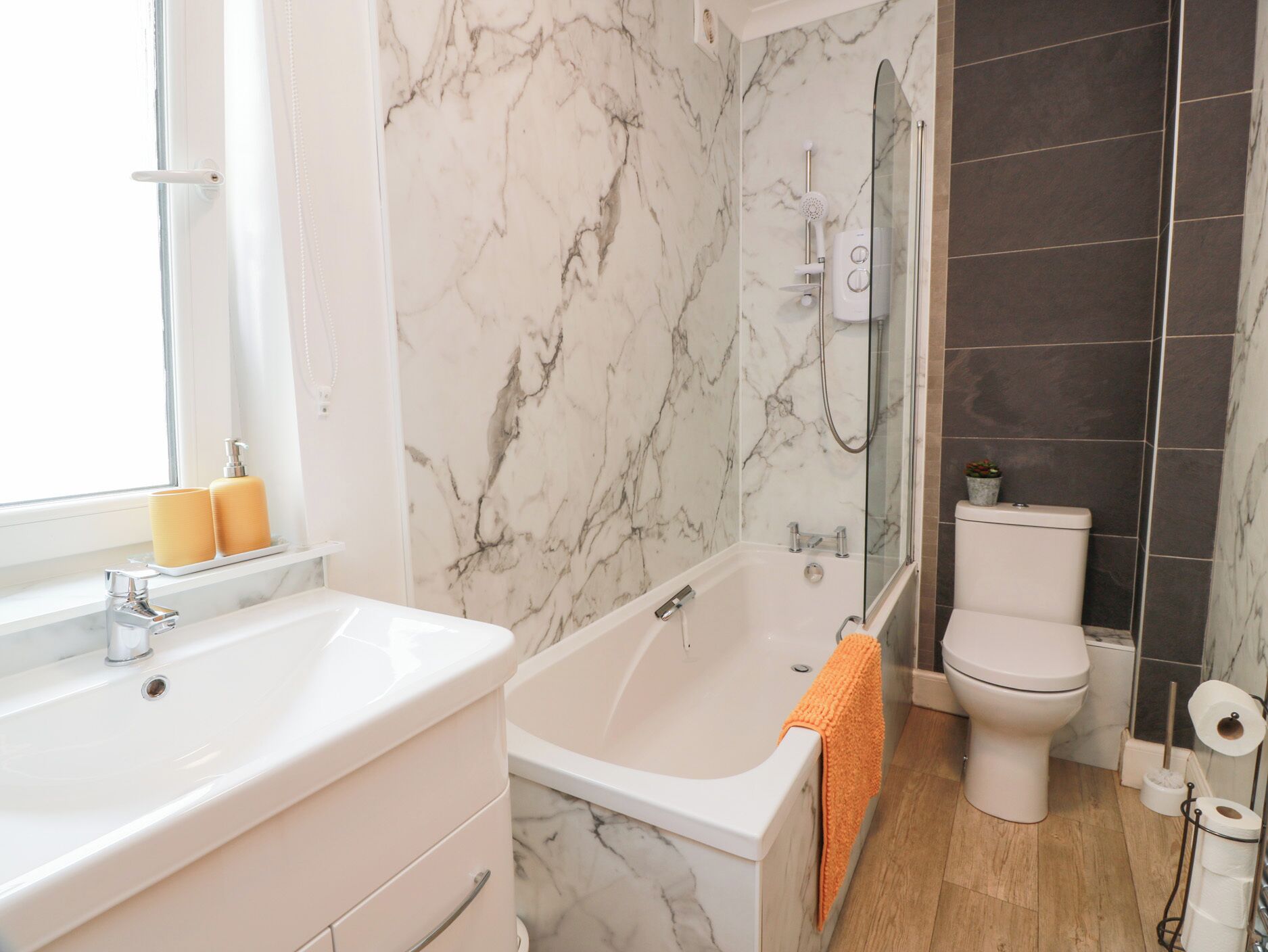 Ein Badezimmer mit Marmorwand, einer Badewanne, einer Toilette und einem Waschbecken.