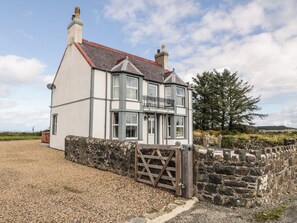 A two-story house with a stone wall and a gravel driveway. - Bryn Ffynnon (Pwllheli)