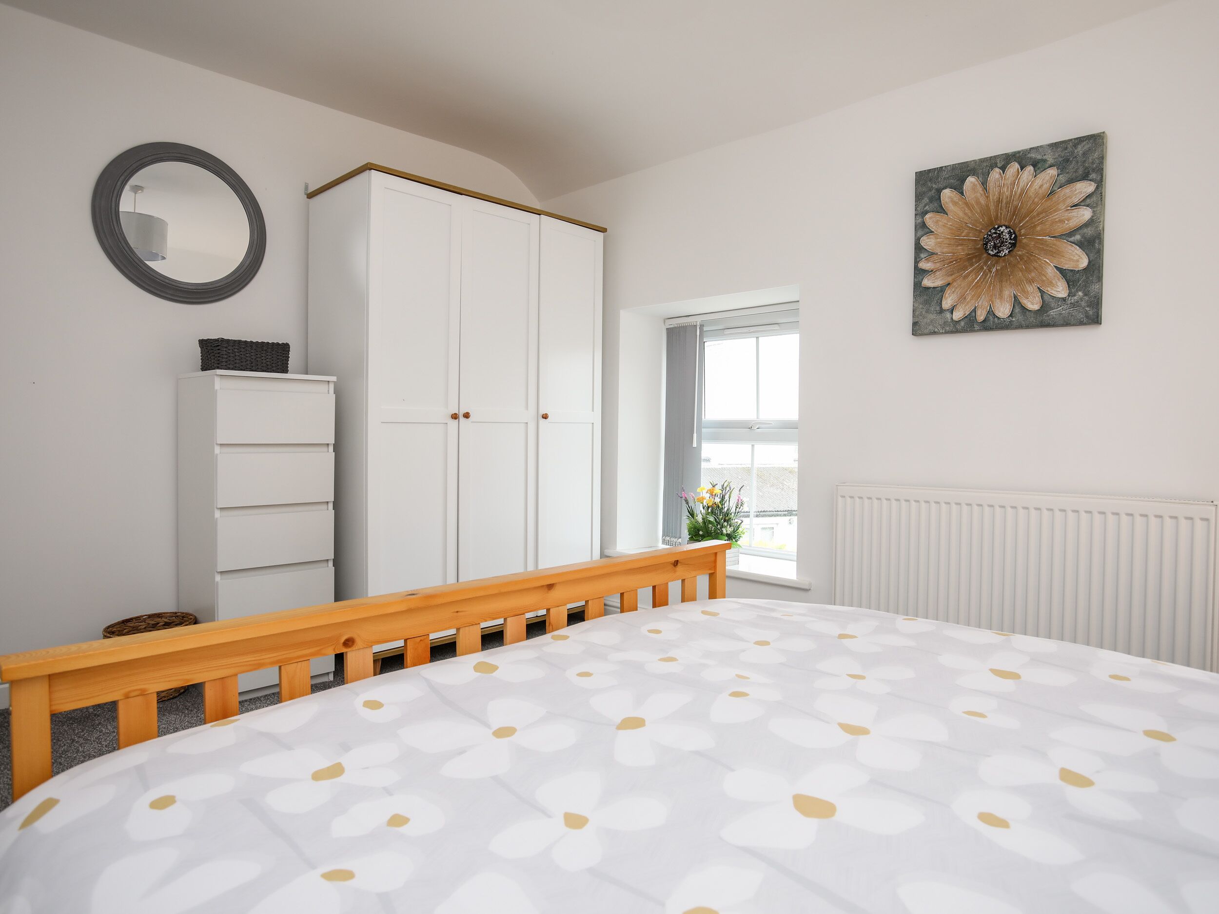 A bedroom with a bed, a wardrobe, a mirror, and a window with a view.