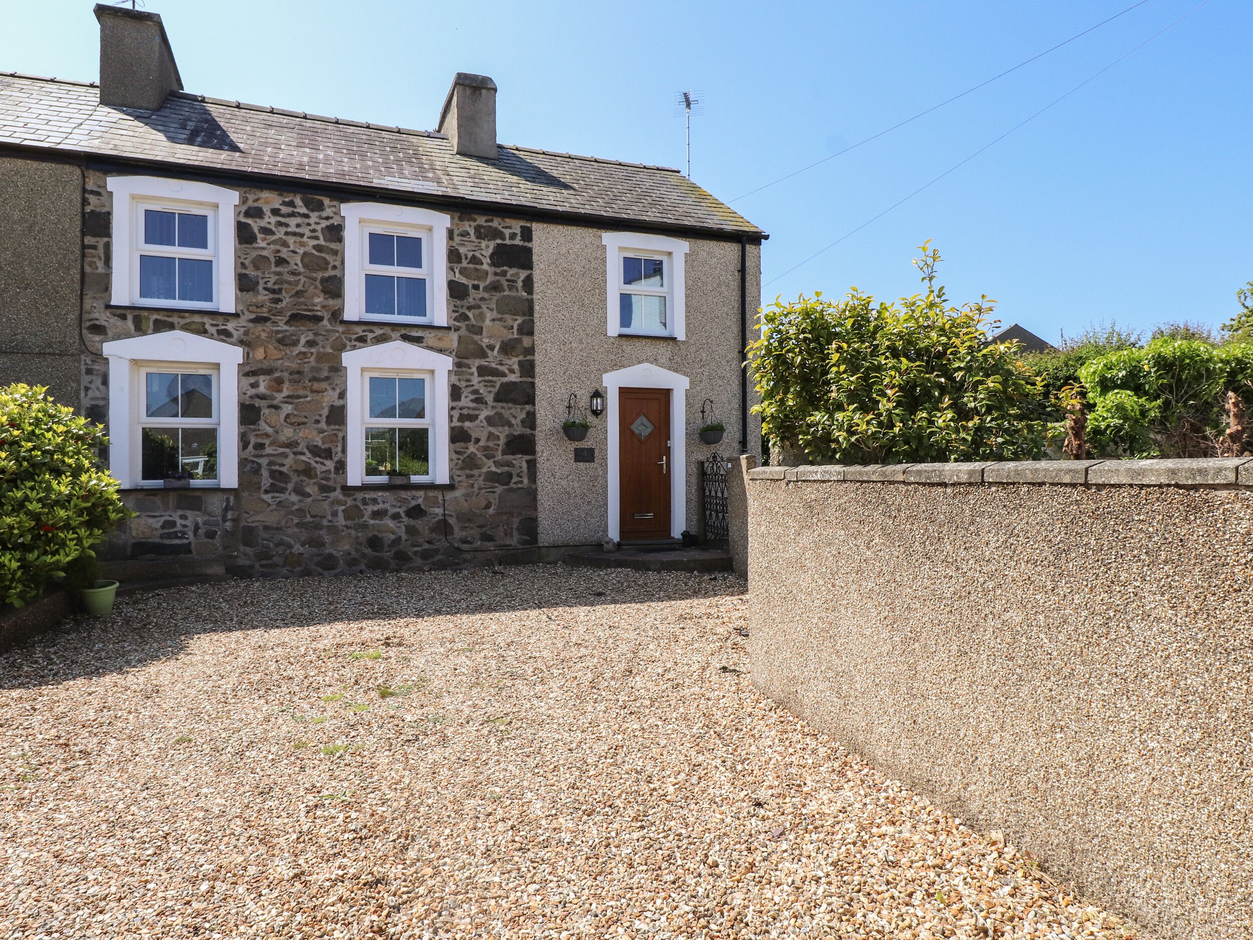 A stone house with a gravel driveway, a wooden door, and a small garden area.