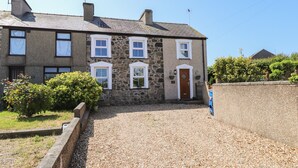 A stone building with a gravel driveway and a wooden door. - Bwthyn Defaid (Pwllheli)
