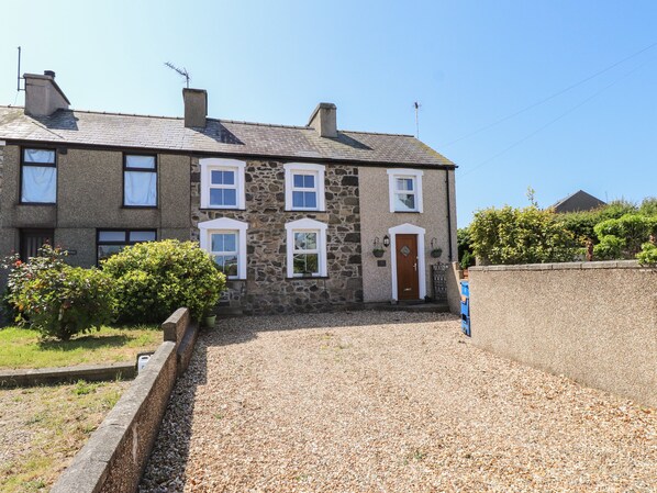 A stone building with a gravel driveway and a wooden door. - Bwthyn Defaid (Pwllheli)