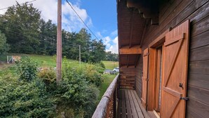 En træhytte med balkon, udsigt over en frodig have og en klar himmel.