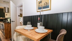 Un comedor con una mesa de madera, dos cuencos blancos, dos copas de vino y una botella de vino.