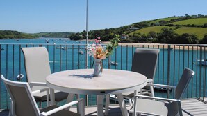 A round table with four chairs on a deck overlooking a bay with boats and hills in the background. - 34 The Salcombe (Salcombe)