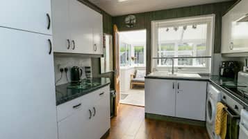 A modern kitchen with white cabinets, a black countertop, and a built-in washing machine.