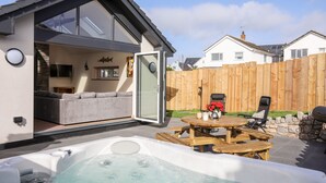 Une maison moderne dotée d’un patio, d’un jacuzzi et d’une terrasse en bois.