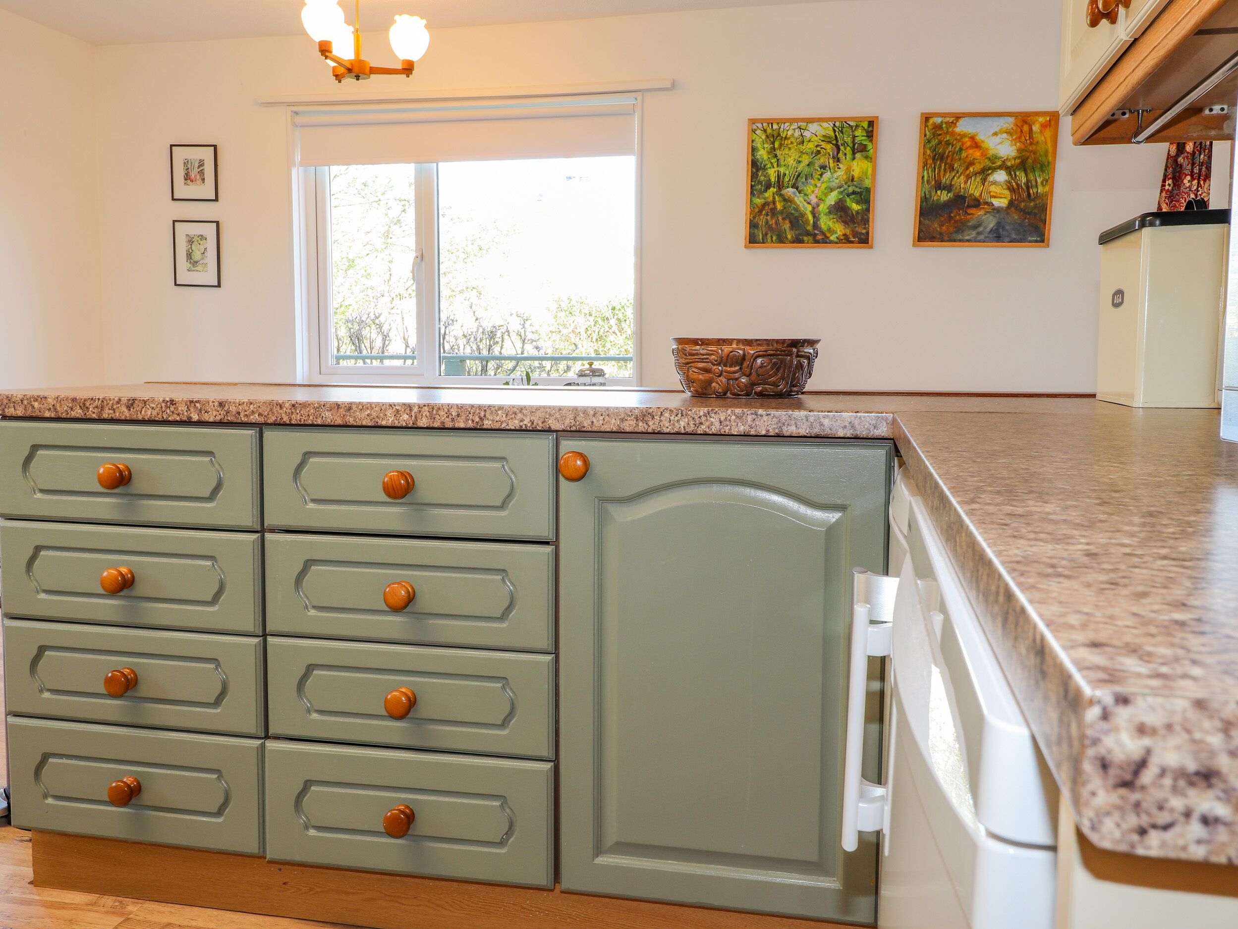 A kitchen with a granite countertop, green cabinetry, and a window with a view.