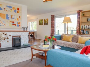 A cozy living room with a fireplace, a sofa, a coffee table, and a bookshelf. - Goldcrest (Newport)
