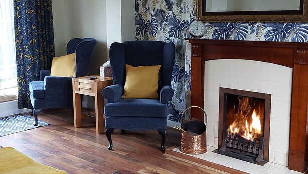 A living room with two armchairs, a wooden coffee table, a fireplace, and a patterned wallpaper. - Ryeby Garth (Hull)