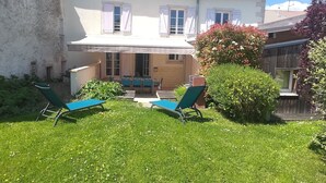 Une maison à deux étages dotée d’un patio aménagé avec du mobilier d’extérieur.