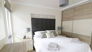 A neatly arranged bedroom with a large bed, bedside tables, and a wardrobe. - 44 Heritage Park (Haverfordwest)
