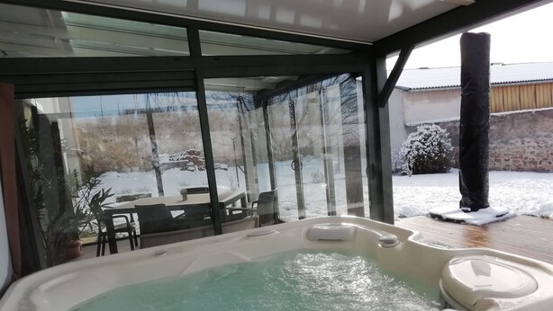 Un bain à remous avec vue sur un espace extérieur enneigé, visible à travers de grandes portes vitrées.