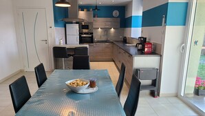 Une cuisine moderne avec un coin repas, comprenant une grande table, des chaises et un saladier rempli de nourriture.