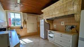Une cuisine avec un plafond en bois, des armoires blanches, un four encastré et une cuisinière.