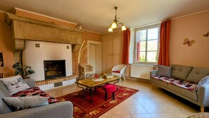Un salon avec une cheminée, un canapé, une table à manger avec des chaises et une fenêtre avec des rideaux.