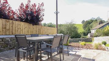 An outdoor patio with a table and chairs, a wooden fence, and a stone wall.