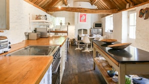 Une cuisine rustique avec des poutres en bois, un grand îlot central et des appareils électroménagers simples.