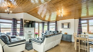 A modern living room with a sofa, a dining table, and a fireplace. - Lakeview Lodge (Carnforth)