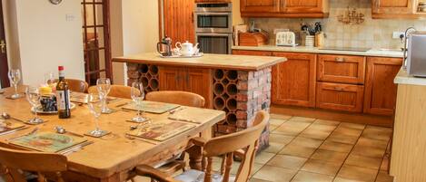 A kitchen with wooden cabinets, a brick island, and a dining table set for four.