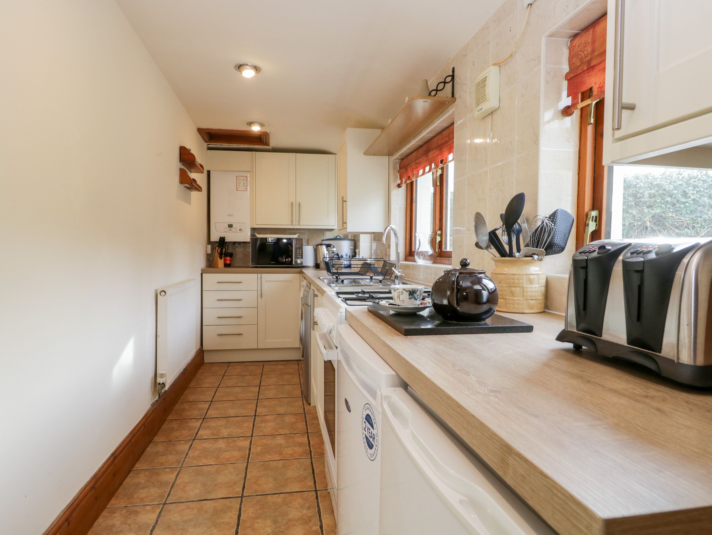 A compact kitchen with white cabinets, a microwave, a kettle, and a toaster.