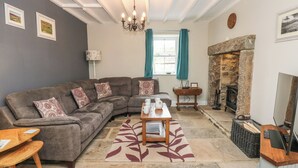 A living room with a sectional sofa, a coffee table, a fireplace, and a stone wall. - White Lea (Richmond)