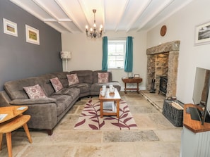 A living room with a sectional sofa, a coffee table, a fireplace, and a stone wall.