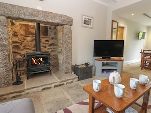 A stone fireplace with a TV and coffee mugs on a table.