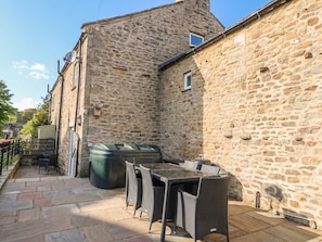 A stone building with outdoor seating and a large trash bin.