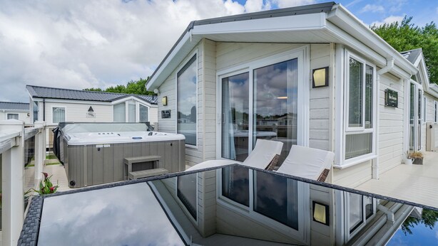 Ein modernes Haus mit Whirlpool, großen Fenstern und einer Terrasse.
