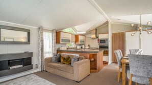 Eine moderne Küche mit einer zentralen Kochinsel, ein Essbereich mit Tisch und Stühlen, eine Couch mit Kissen und ein Kamin.