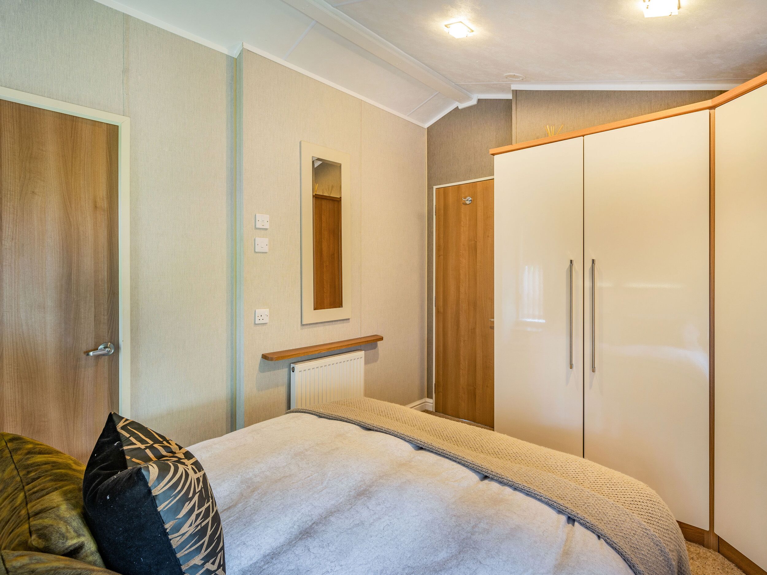 A bedroom with a bed, a wardrobe, a mirror, and a radiator.