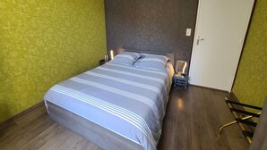 Makuuhuone, jossa on sänky, yöpöydät, lamppu, ovi ja tuoli.