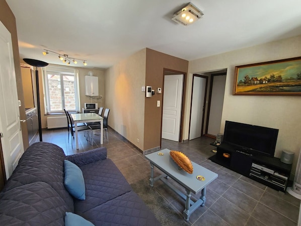 Un salon comprenant un canapé, une table basse, une cheminée, un téléviseur et un coin repas avec une table et des chaises.