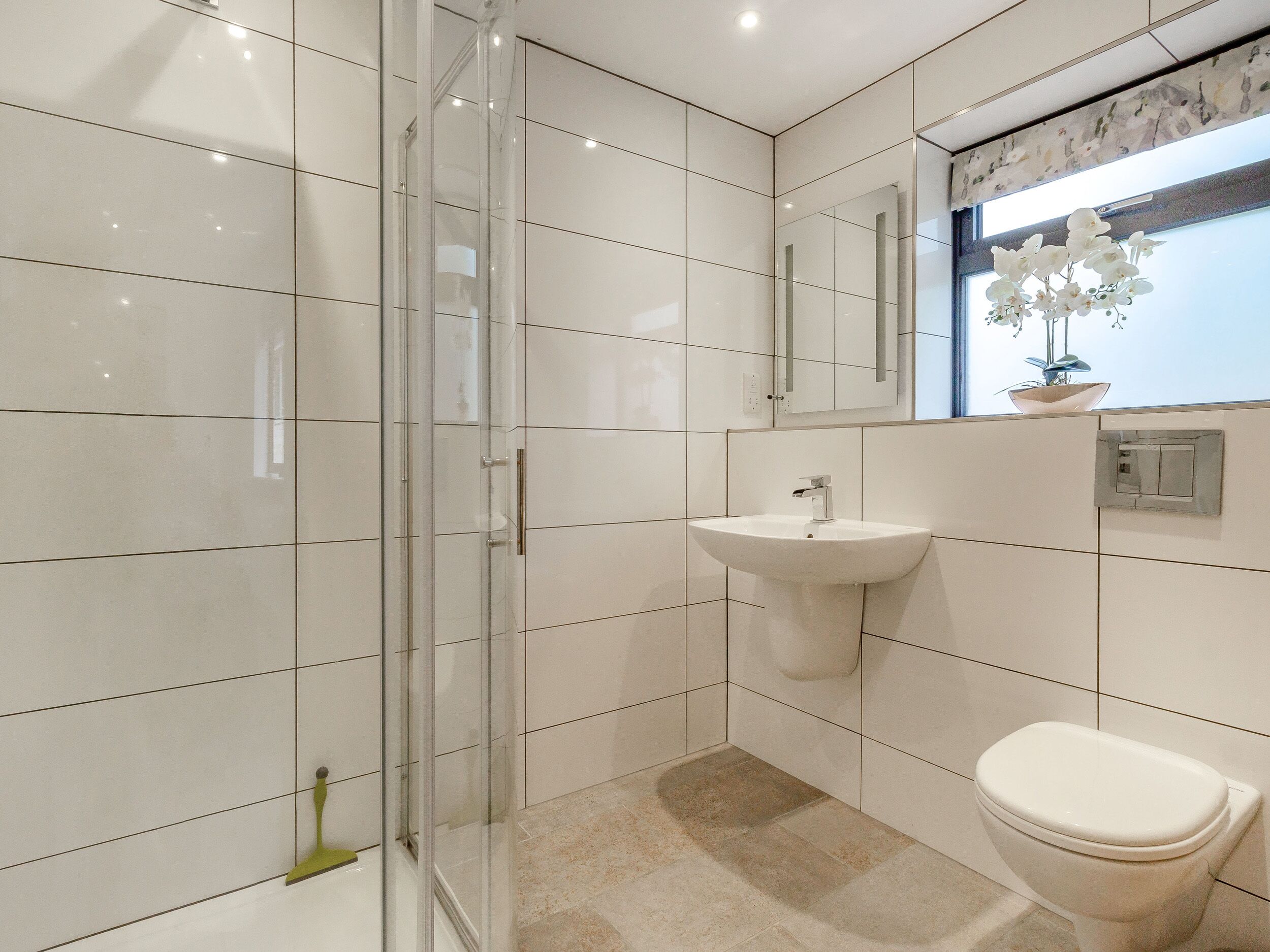 A modern bathroom with a glass shower enclosure, a white sink, and a toilet.