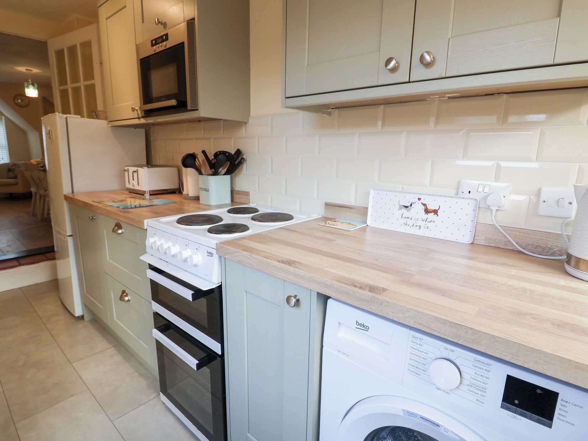 A compact kitchen with a stove, oven, microwave, and a washing machine.