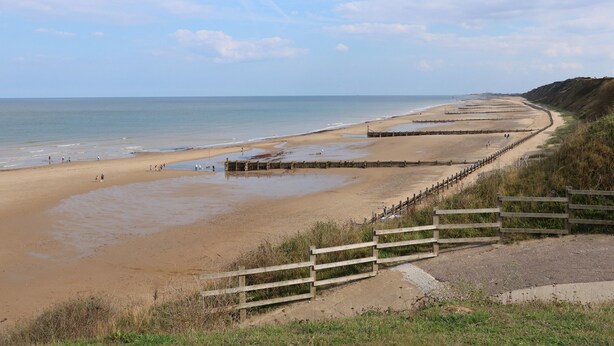 A coastal beach with wooden walkways and a sandy shore.