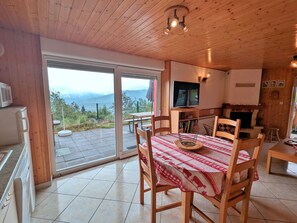 Een houten interieur met een eethoek, een open haard en een televisie.