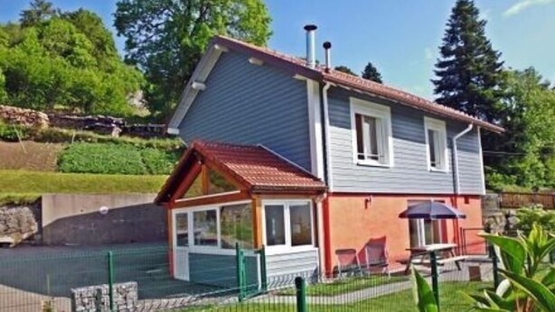 A two-story house with a red roof, a fenced backyard, and a small patio area. - Independent house with garden, terrace and fireplace in Saulxures-sur-Moselotte (Saulxures-sur-Moselotte)