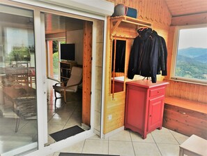 Una habitación con interior de madera, un armario rojo, una silla, un televisor y vistas al exterior.