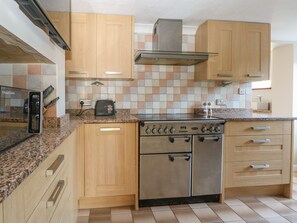 A kitchen with wooden cabinets, a stainless steel stove, and a tiled backsplash. - 1 Paythorne Farm Cottages (Henfield)