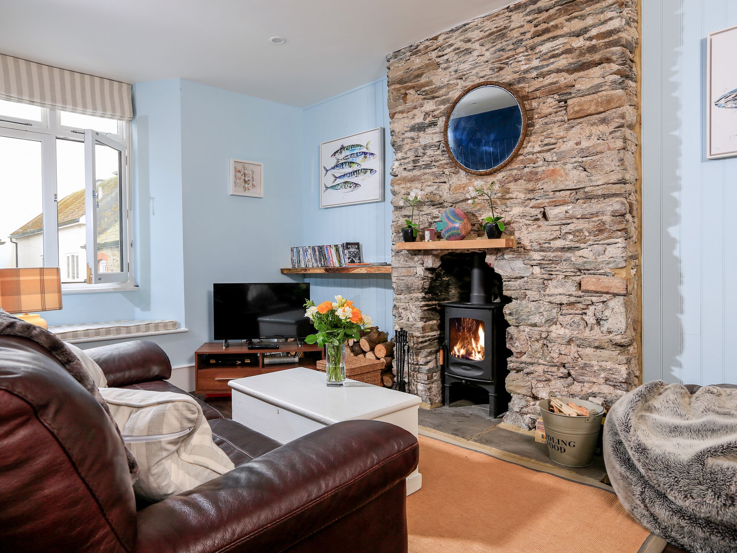 A cozy living room with a stone fireplace, a television, and leather furniture.