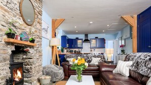 Un salon chaleureux avec une cheminée en pierre, une table basse blanche et un canapé en cuir marron.