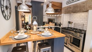 A modern kitchen with a central island, stainless steel appliances, and a clock on the wall. - 1 Oakleys (Holmfirth)