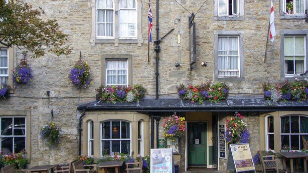 A stone building with multiple windows, flower boxes, and outdoor seating. - Town Head Cottage (Skipton)