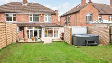 A residential property with a backyard, a hot tub, and a conservatory.
